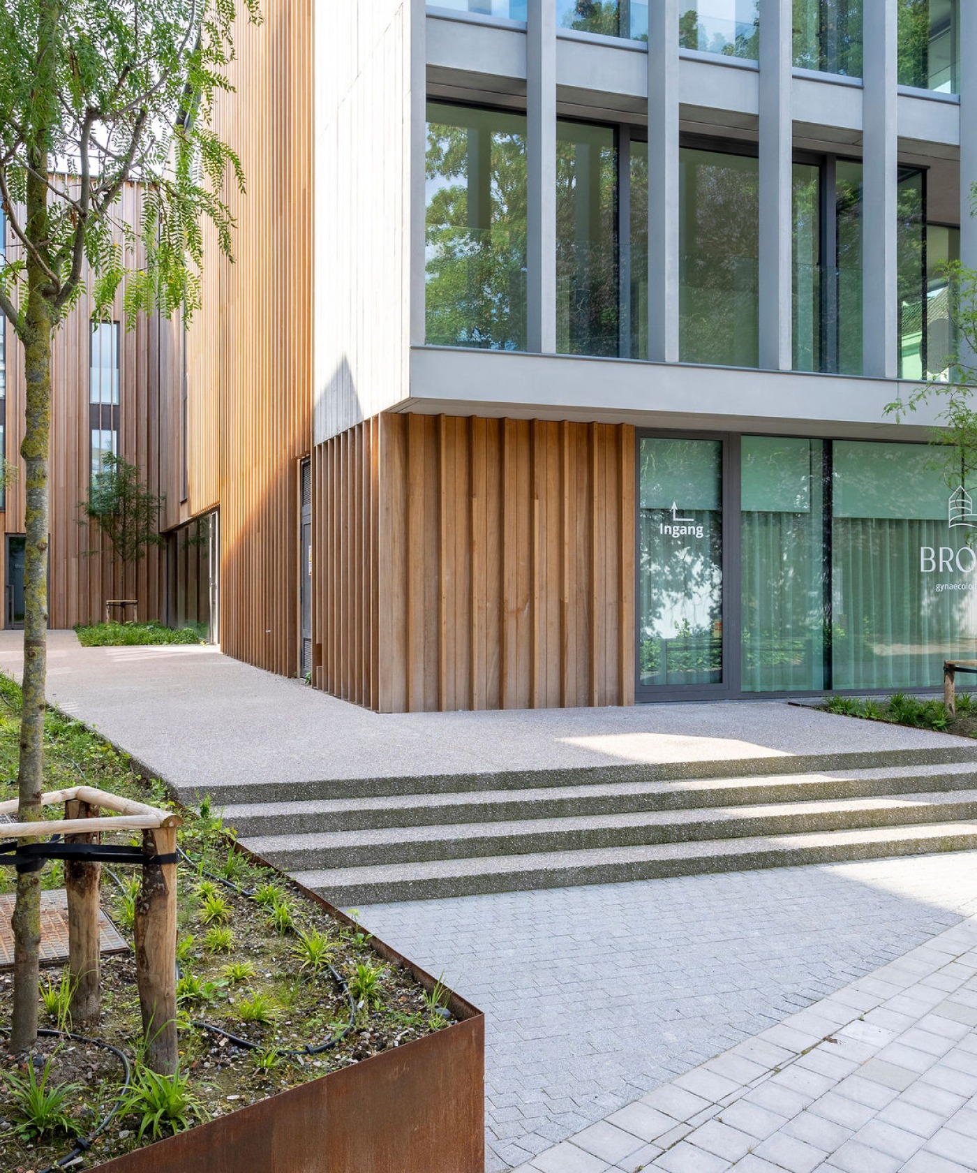 Groene entree bij het Broelhotel met houten gevelbekleding en minimalistische beplanting