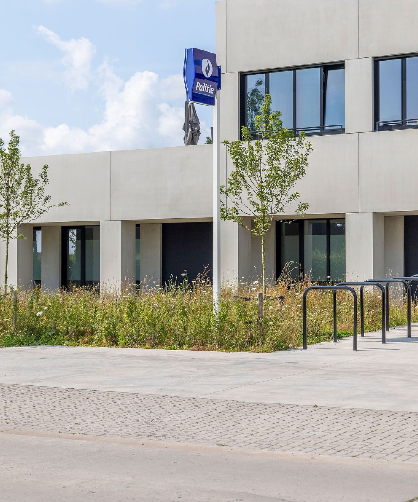 Vooraanzicht van het politiekantoor Torhout met groene landschapsinrichting.