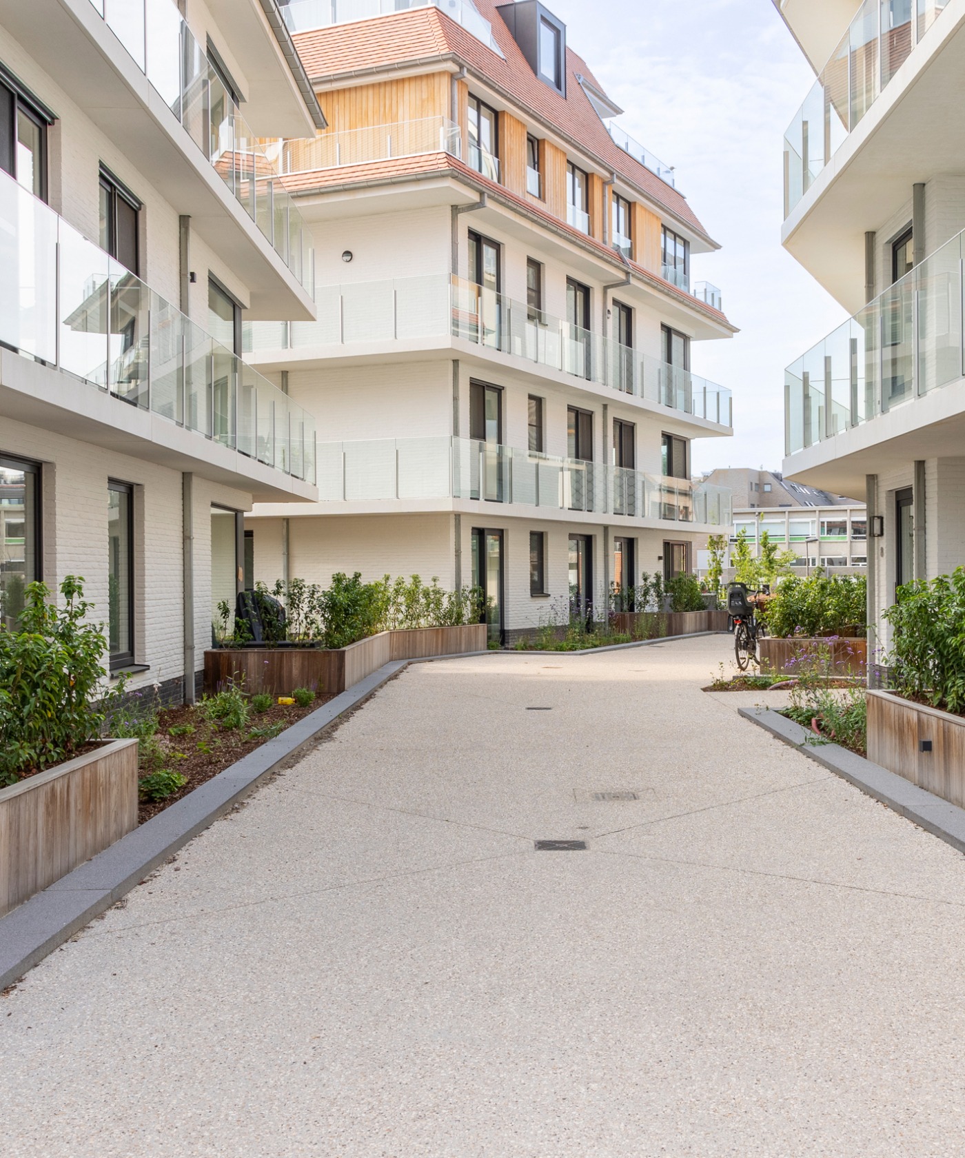 Doorgang tussen de gebouwen met aangelegde bloembakken en groene planten