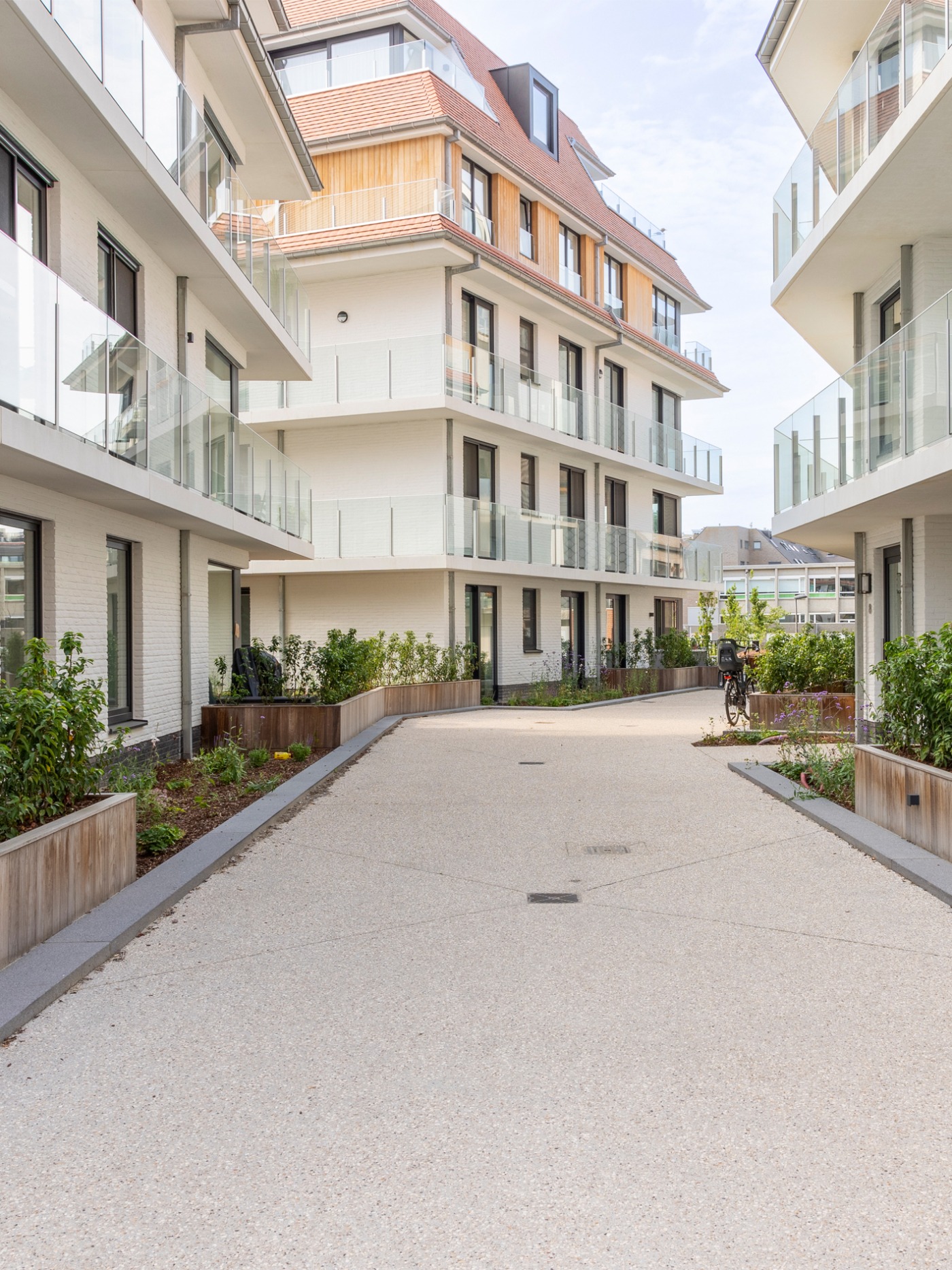 Doorgang tussen de gebouwen met aangelegde bloembakken en groene planten