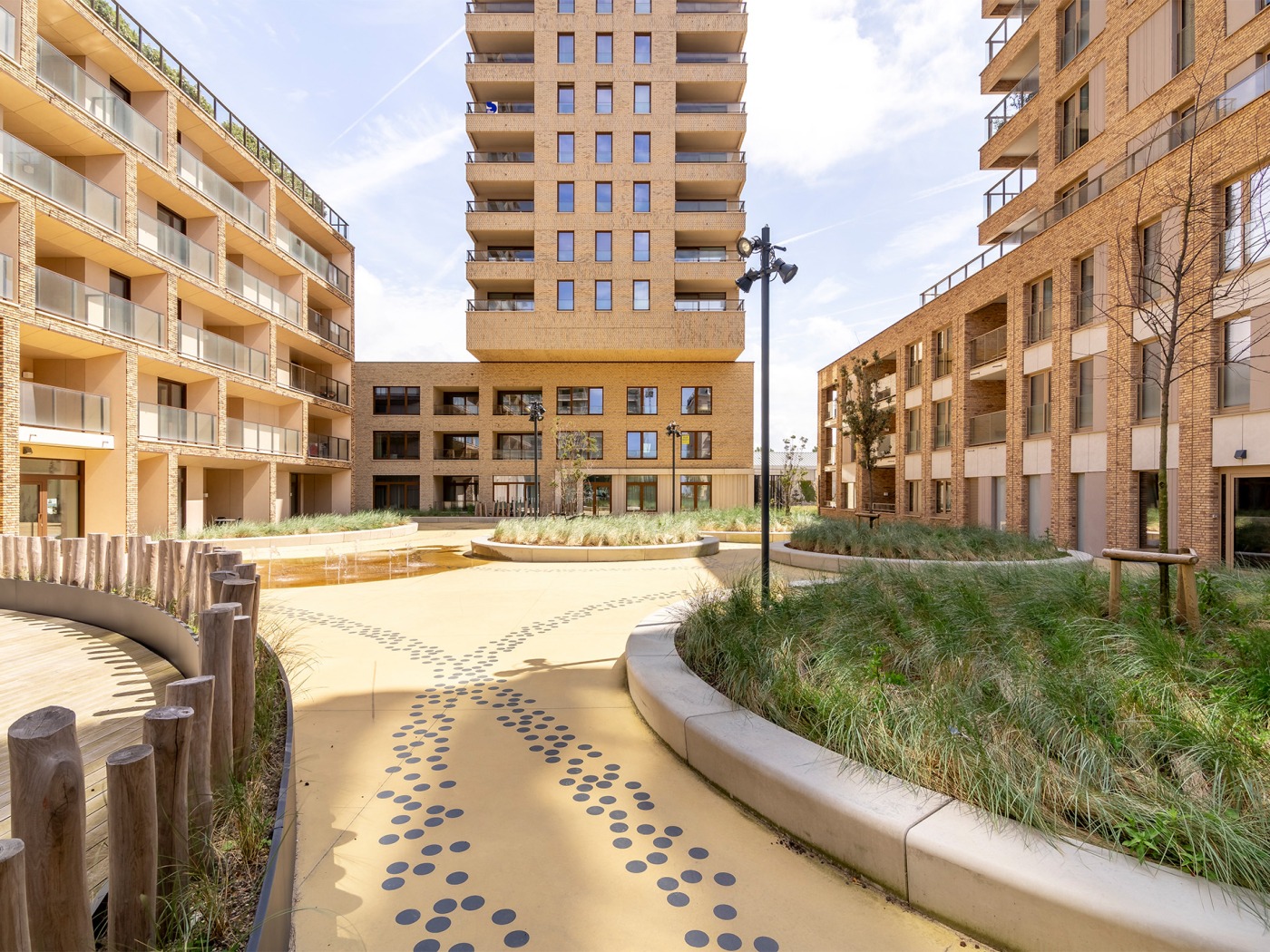 Grote binnentuin met groene eilanden, houten ligbanken en fonteinen bij O'Sea wooncomplex, Oostende